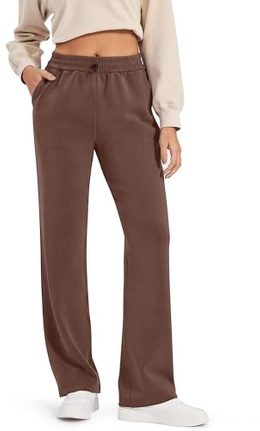 Model in een bruine wijde joggingbroek met zakken aan de zijkant en een beige crop top sweater.