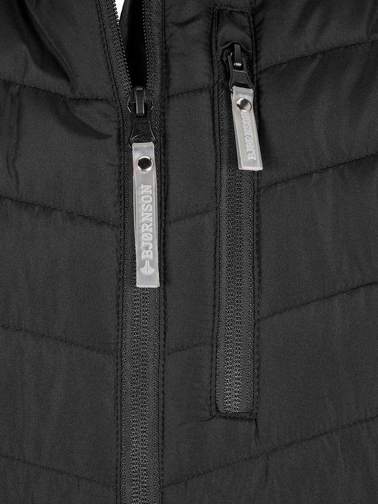 Detail van ritsen op zwarte bodywarmer met "BJØRNSON"-logo op de labels.