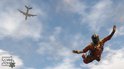 Parachutist springt uit vliegtuig met een stadsgezicht en wolken op de achtergrond.