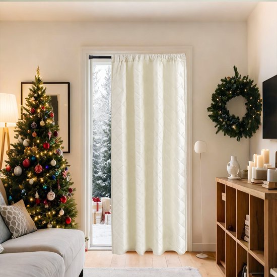 Een sfeervolle woonkamer met een kerstboom, bank en open kast, met een beige thermisch gordijn dat een deur naar de besneeuwde buitenwereld afsluit.