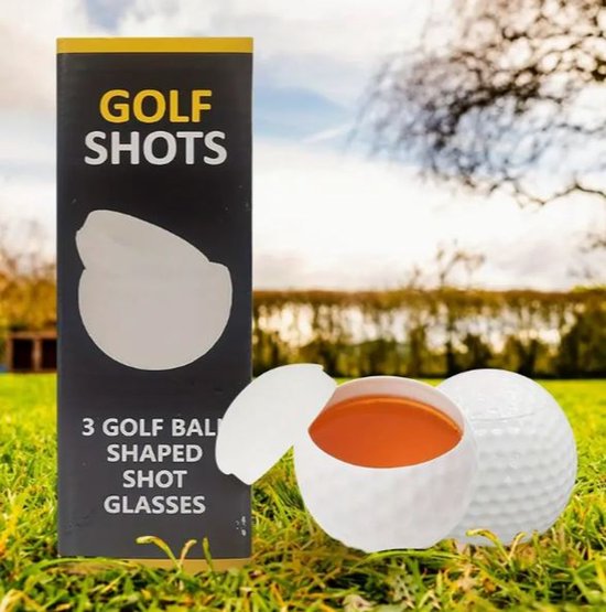 Een gevuld golfbal shotglas en een gesloten golfbalglas op gras, naast een verpakking.