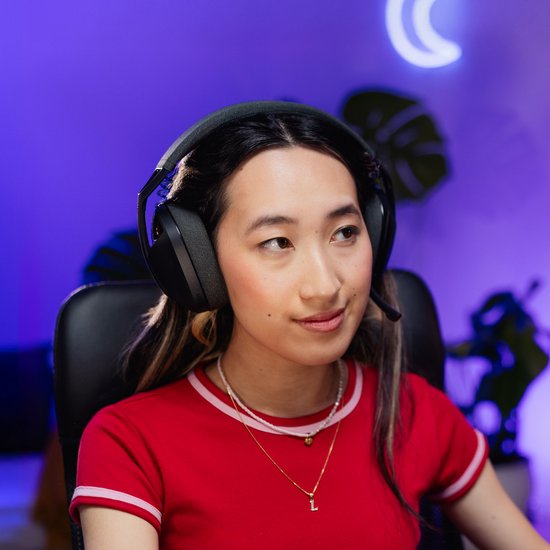 Een jonge vrouw met lang zwart haar en een rode top draagt een zwarte Logitech G gaming headset.