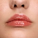Close-up van lippen met sproeten, bedekt met glanzende, lichtroze lipgloss.