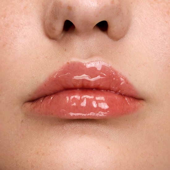 Close-up van lippen met sproeten, bedekt met glanzende, lichtroze lipgloss.