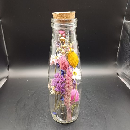 Glazen fles met kurk, gevuld met gedroogde bloemen in diverse kleuren zoals roze, paars, geel en wit.