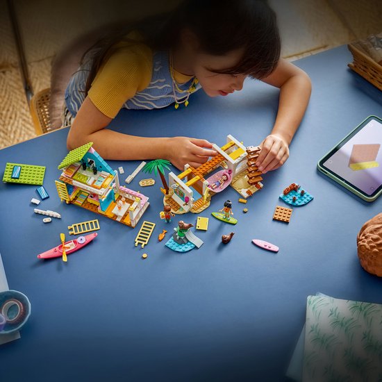 Meisje speelt met LEGO Friends strandhuis set op tafel.
