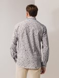 Man van achteren met een grijs overhemd met bloemenprint en beige broek.