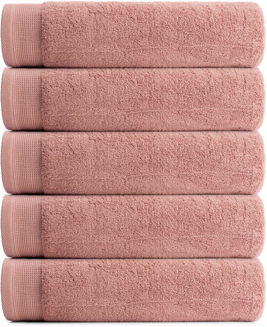 Cinq serviettes rose doux empilées les unes sur les autres, avec une bordure tricotée nette.