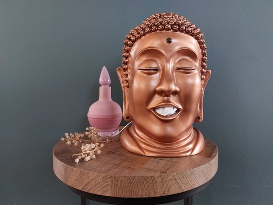 Bronzen Boeddha hoofd tissuehouder op een ronde houten tafel met decoratie.