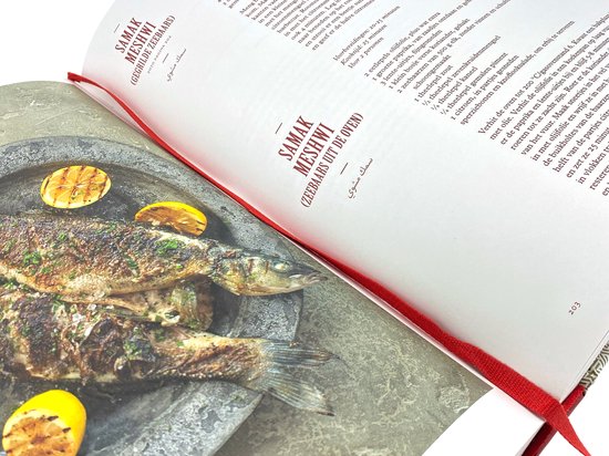 Open kookboek met recept "Samak Meshwi" en een afbeelding van gegrilde vissen met citroen.