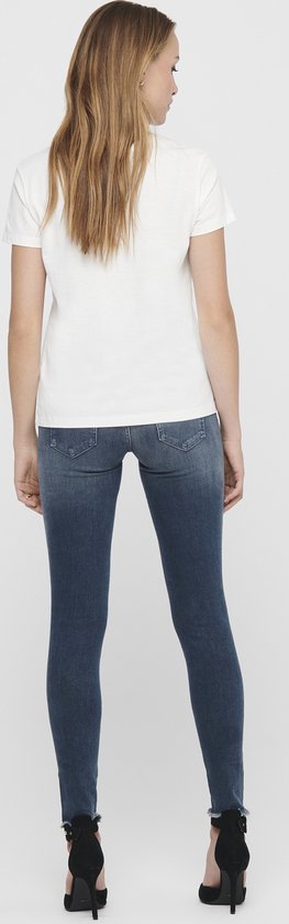 Achterkant van model met blauwe skinny jeans met raw-edge enkelbroekspijpen.