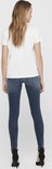 Achterkant van model met blauwe skinny jeans met raw-edge enkelbroekspijpen.