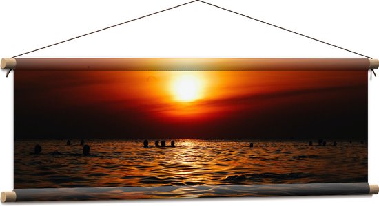 WallClassics - Textielposter - Zwemmende Mensen in Zee bij Ondergaande Zon - 90x30 cm Foto op Textiel