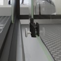 Rouleau de porte coulissante noir avec une poignée blanche sur une porte de douche transparente.