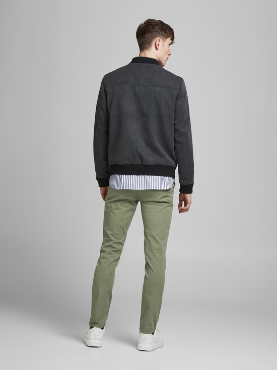 Man met smalle, lichtgroene broek en donkergrijs jack, achterkant.