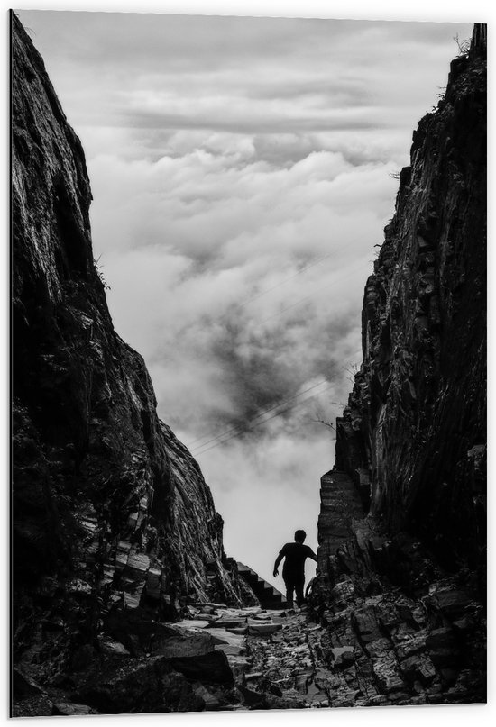 WallClassics - Dibond - Man tussen Rotsen boven Wolken in Zwart-wit - 60x90 cm Foto op Aluminium (Wanddecoratie van metaal)