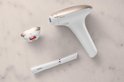 Wit Philips Lumea IPL ontharingsapparaat met rosé gouden accenten, een opzetstuk en een precisietrimmer op een lichte achtergrond.