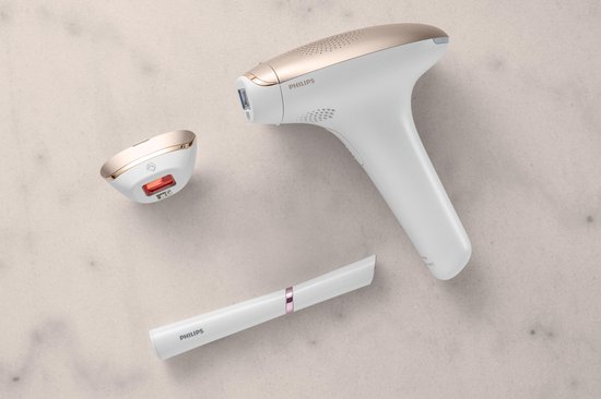 Wit Philips Lumea IPL ontharingsapparaat met rosé gouden accenten, een opzetstuk en een precisietrimmer op een lichte achtergrond.