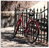 WallClassics - PVC Schuimplaat- Rode Fiets geparkeerd bij Gebouw - 50x50 cm Foto op PVC Schuimplaat