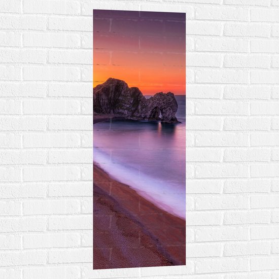 WallClassics - Muursticker - Rotsen aan het Strand met Kalme Zee - 40x120 cm Foto op Muursticker