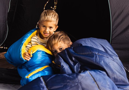 Twee jongens in een tent, deels verborgen in blauwe slaapzakken.