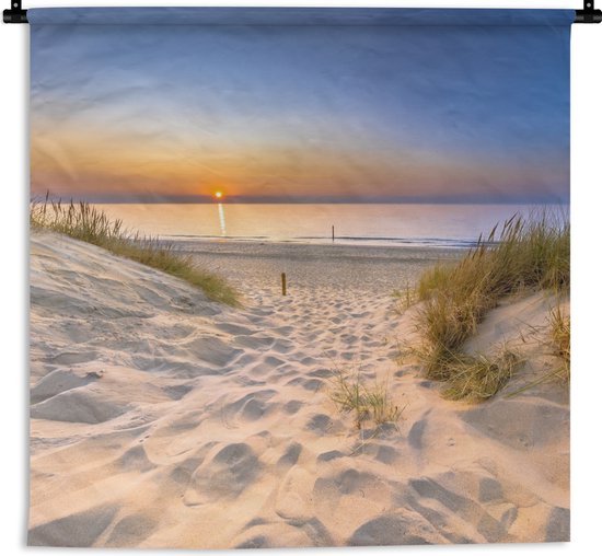 Wandkleed met een zonsondergang over duinen en strand, aan een zwarte roede.
