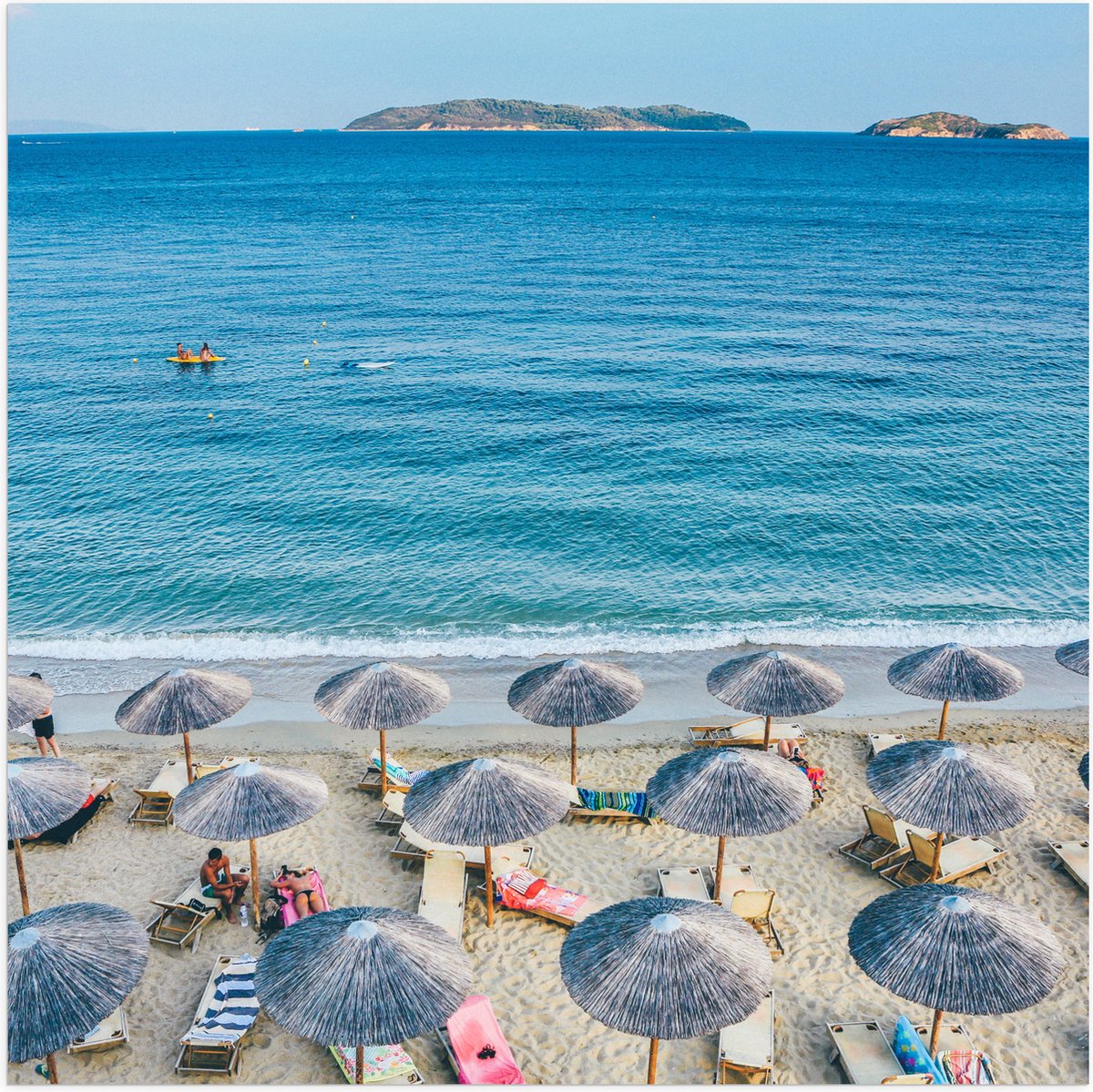 Poster Glanzend – Rieten Parasols met Ligbedjes op het Strand - 50x50 cm Foto op Posterpap