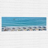 WallClassics - Muursticker - Rieten Parasols met Ligbedjes op het Strand - 120x40 cm Foto op Muursticker