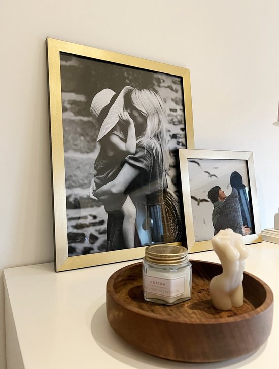 Cadre photo doré avec une photo noir et blanc d'une mère tenant son enfant. Un cadre plus petit à côté montre un couple.