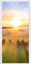 Deursticker Kleurrijke zonsopkomst boven een kalm landschap - 95x235 cm - Deurposter