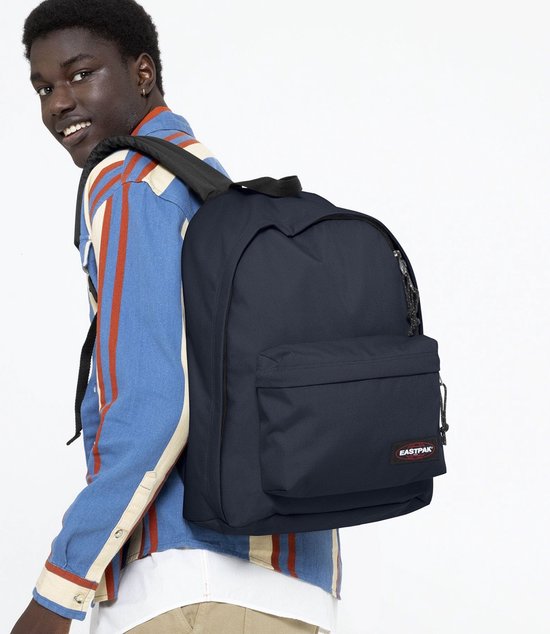 Jonge man draagt een donkerblauwe Eastpak rugzak over zijn schouder.