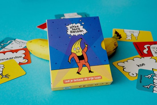 Kaartspel 'Dikke Dans Banaan' met dansende banaan op de verpakking. Omringd door losse kaarten en bananen op blauwe achtergrond.