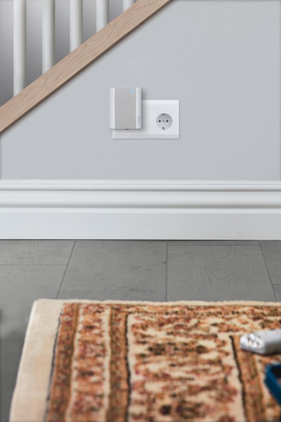 Witte Ring Chime naast een stopcontact bij een trap, met kleed op de vloer.