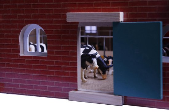 Speelgoedboerderij met zwart-wit koeien die eten uit een voerbak.