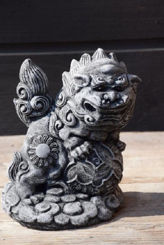 Grijze stenen foo dog tuinbeeld, zittend op sokkel, detail van gezicht en lichaam.