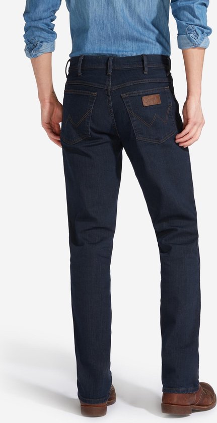 Achteraanzicht van een donkerblauwe Wrangler jeans met regular fit, voorzien van een bruin Wrangler-logo op de zak.