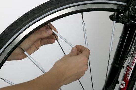 Handen plaatsen zilverkleurige spaakreflectoren op fietsspaak.