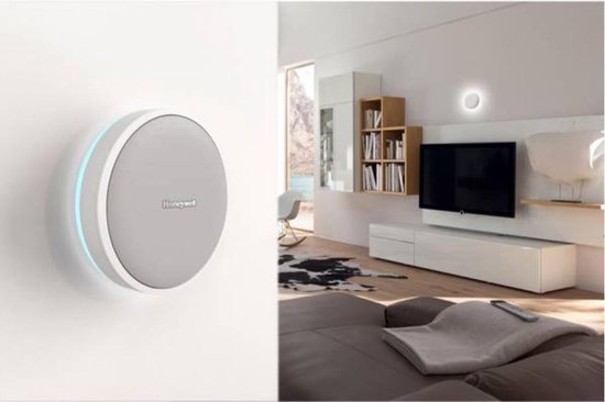 Witte Honeywell deurbel met blauwe led-ring aan de muur in een woonkamer.