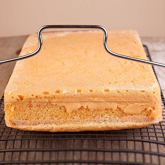 Zilveren taartsnijder met dubbele draad, gebruikt om een vierkante cake op een rooster te snijden.