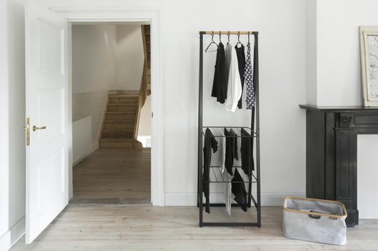 Zwart kledingrek met houten roede, hangende kleding en een mand.