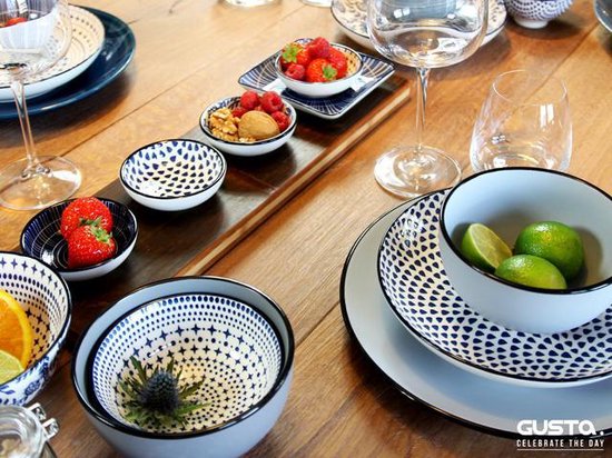 Tafel gedekt met diverse Gusta schalen, borden en glazen, met fruit en nootjes.