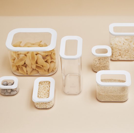 Ensemble de boîtes de conservation transparentes avec couvercles blancs, remplies de pâtes, de riz et d'autres céréales.