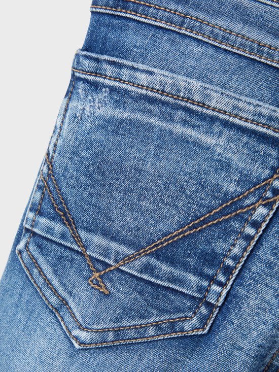 Close-up van de achterzak van een spijkerbroek met decoratieve stiksels en een kleine, lichte beschadiging.