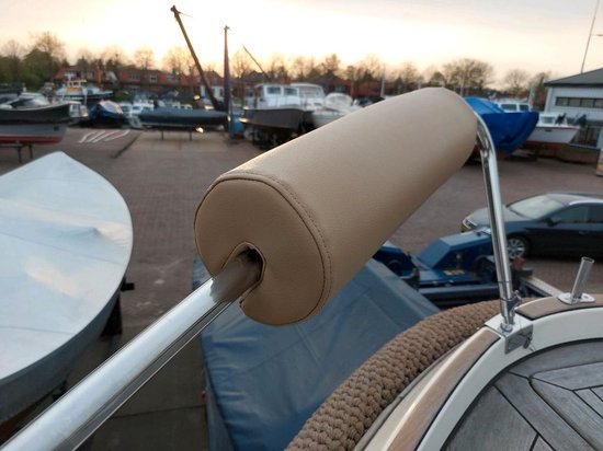 Bruin relingkussen van leerachtig materiaal op een boot, met een metalen steun.