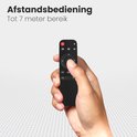 Hand houdt een zwarte afstandsbediening met navigatieknoppen en aan/uit-knop vast.
