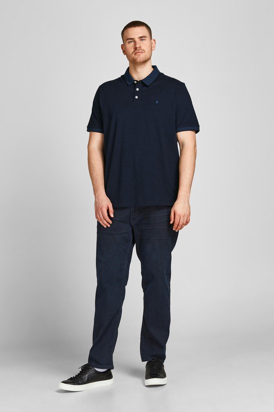Donkerblauw poloshirt met korte mouwen, gedragen door een man met donkere spijkerbroek.