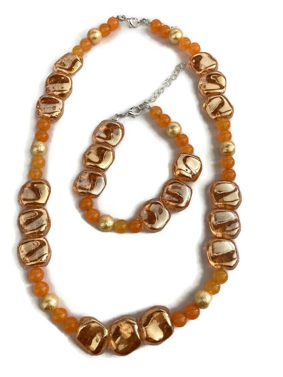 Petra's Sieradenwereld - Handgemaakte sieradenset (ketting en armband) met oranje glaskralen en ijsparels en oranje goudkleurige schelpkralen (906)