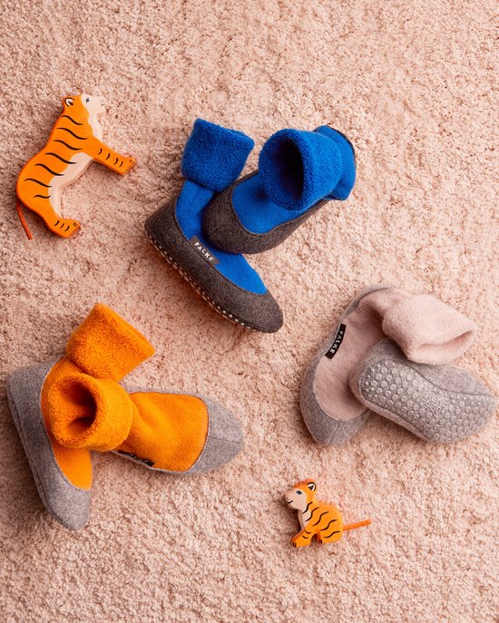 Drie paar Falke huissokken in blauw, oranje en roze/grijs met een grijze zool en twee speelgoedtijgers.