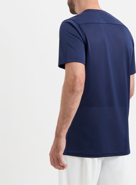 Donkerblauw Nike sportshirt, achterkant zichtbaar. Man draagt witte korte broek en donkerblauwe sokken.