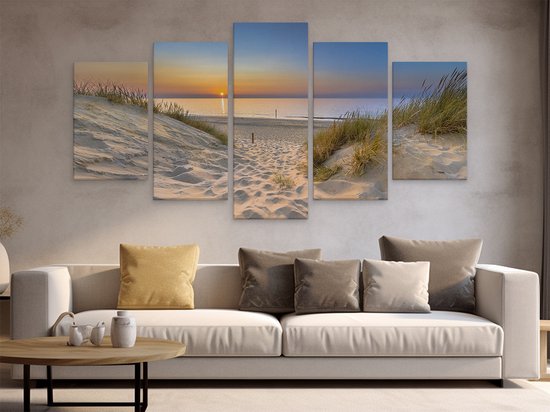 Vijfluik van een strand met duinen en zee bij zonsondergang, hangend boven een bank.